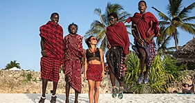 Four masses in traditional red clothes and European girl jumping on the beach