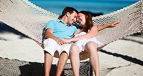 Young romantic couple relaxing in hammock on tropical beach of Zanzibar island